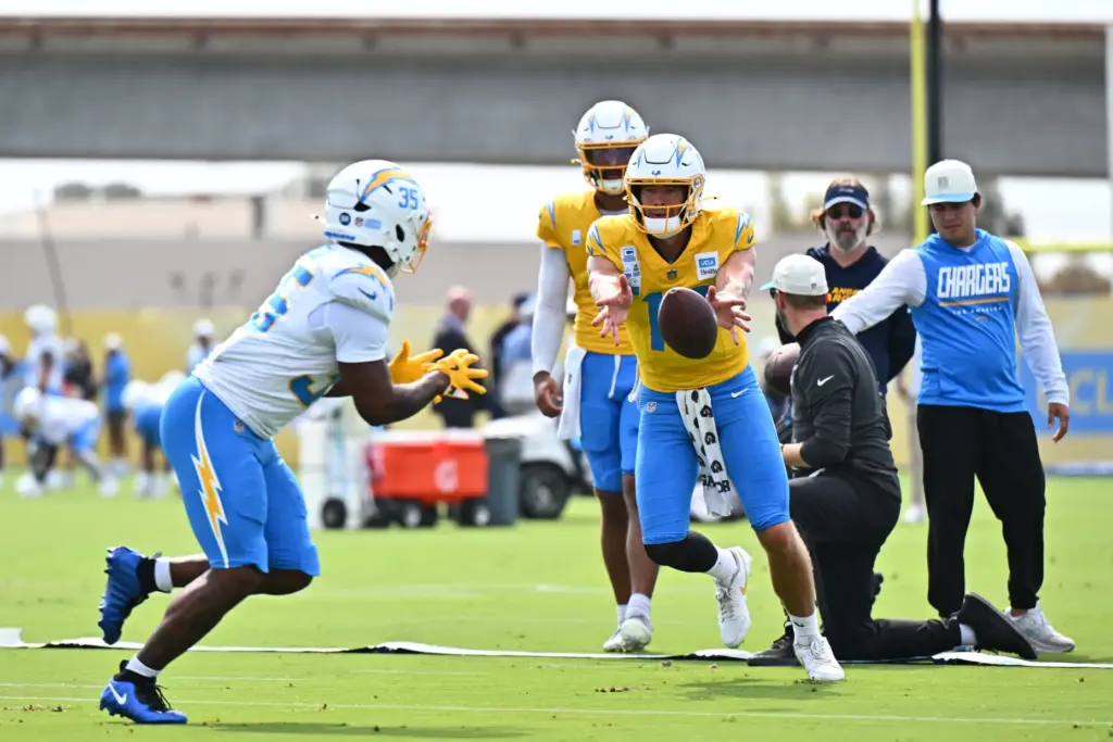 Chargers quarterback Justin Herbert, center, runs a drill with running...