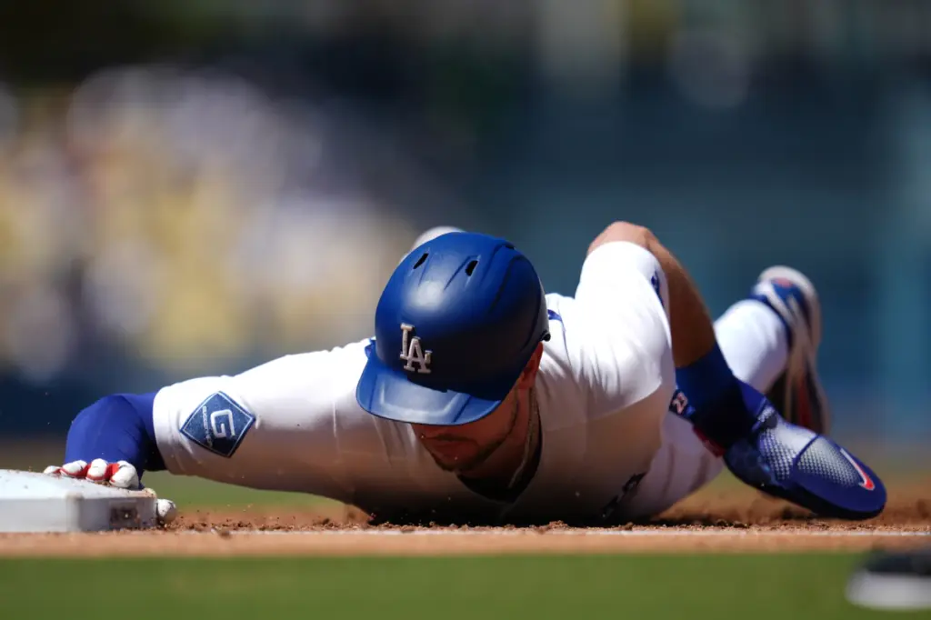 Dodgers’ Kyle Tucker slides back to first base during the...