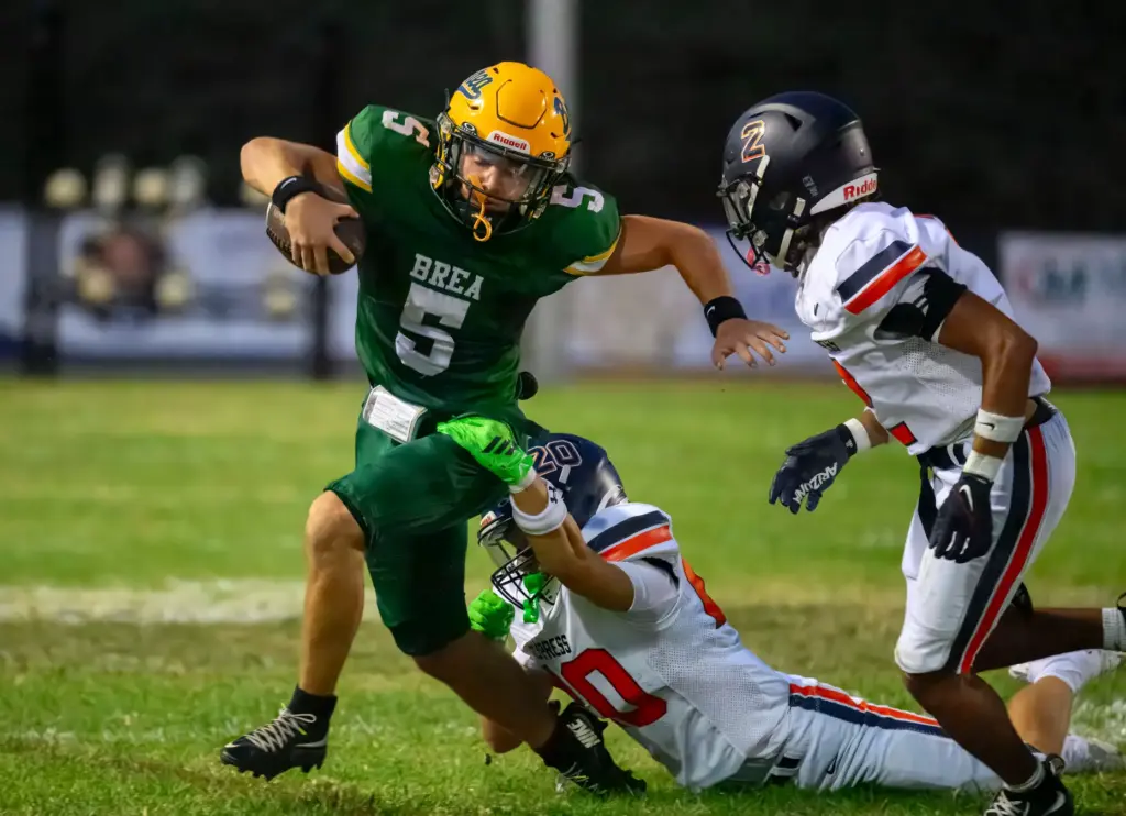 Brea Olinda quarterback Gavyn Nicholson, left, gets away from Cypress...