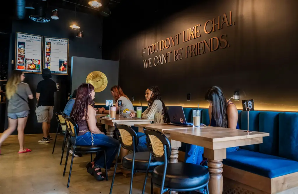 Customers enjoy chai under a sign on the wall that...