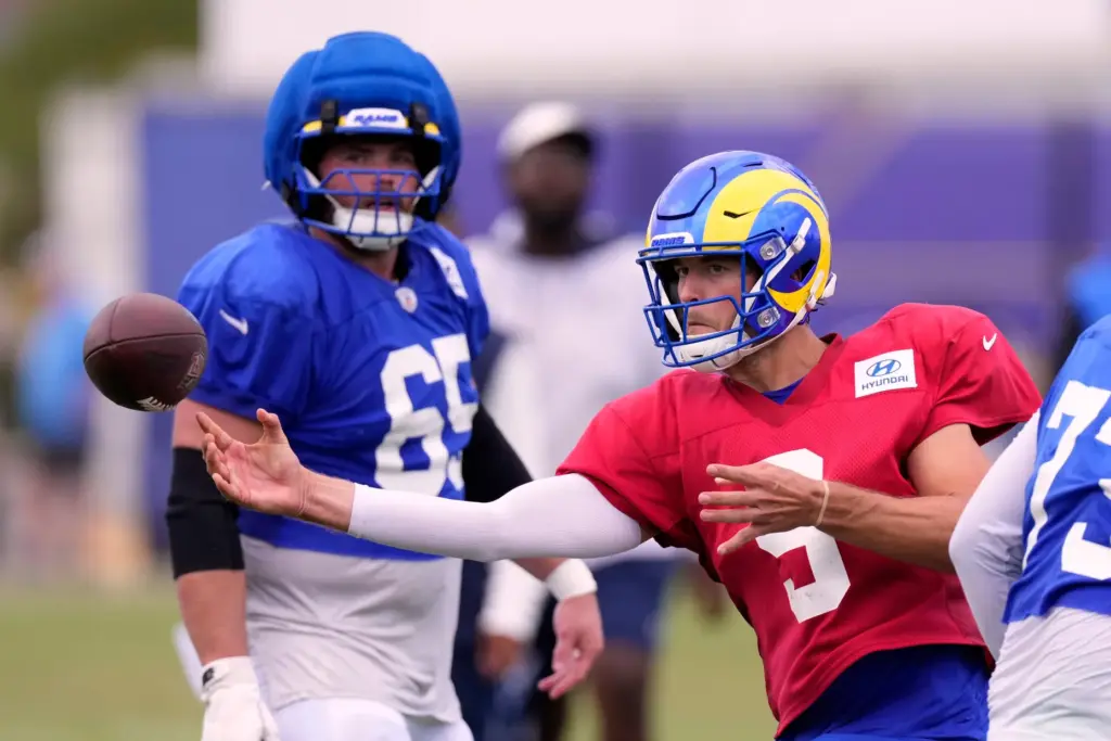 Rams quarterback Matthew Stafford, right, sidearms a pass as center...
