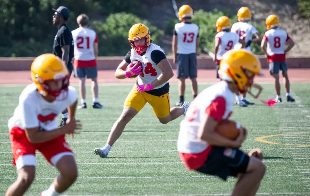 Mission Viejo High School players run plays during practice in...