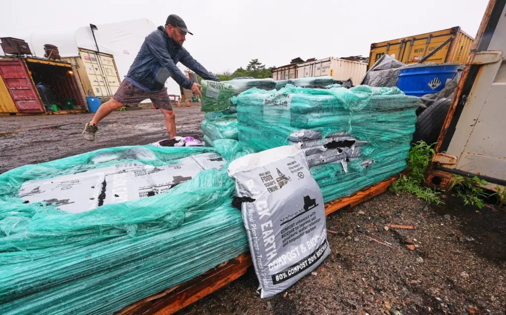 Justin Sandler adds a bag of compost to a pallet...
