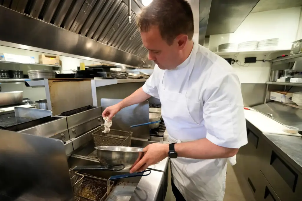 Executive chef Benjamin Hasty drops a breaded green crab into...