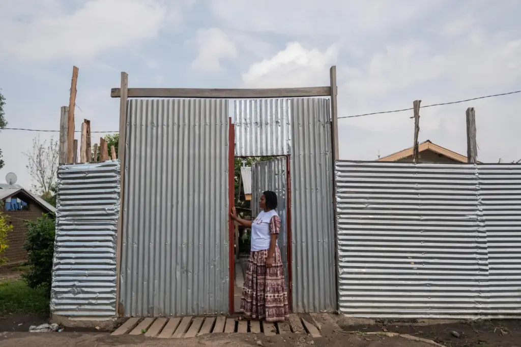 Esther Lutula stands outside her house.
