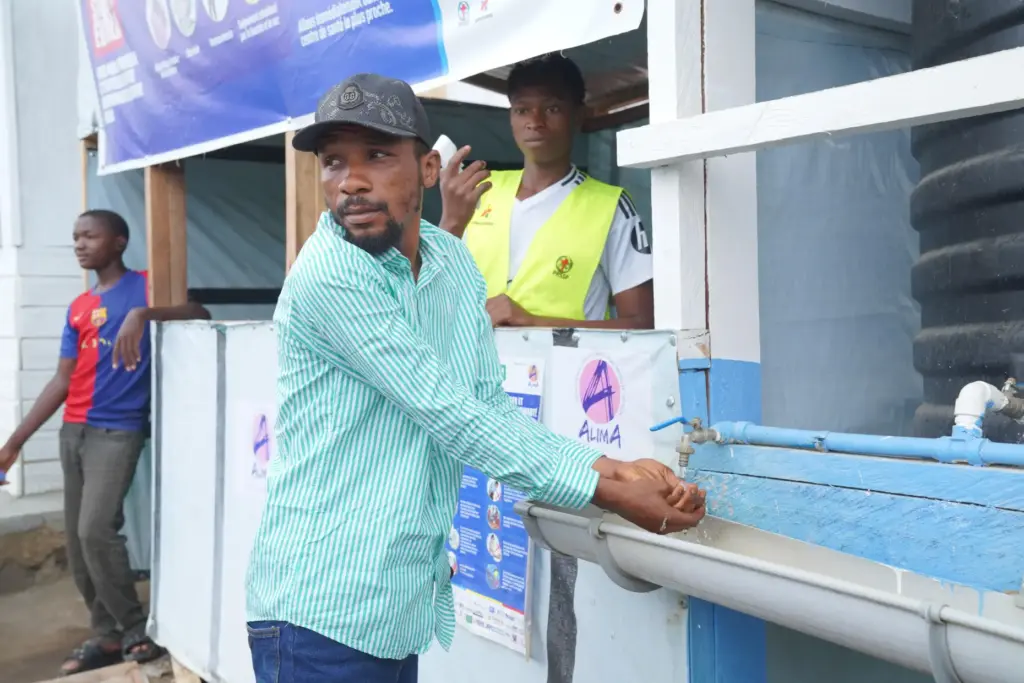 Wiza Bondele washes his hands upon arrival at the Ebola treatment center.