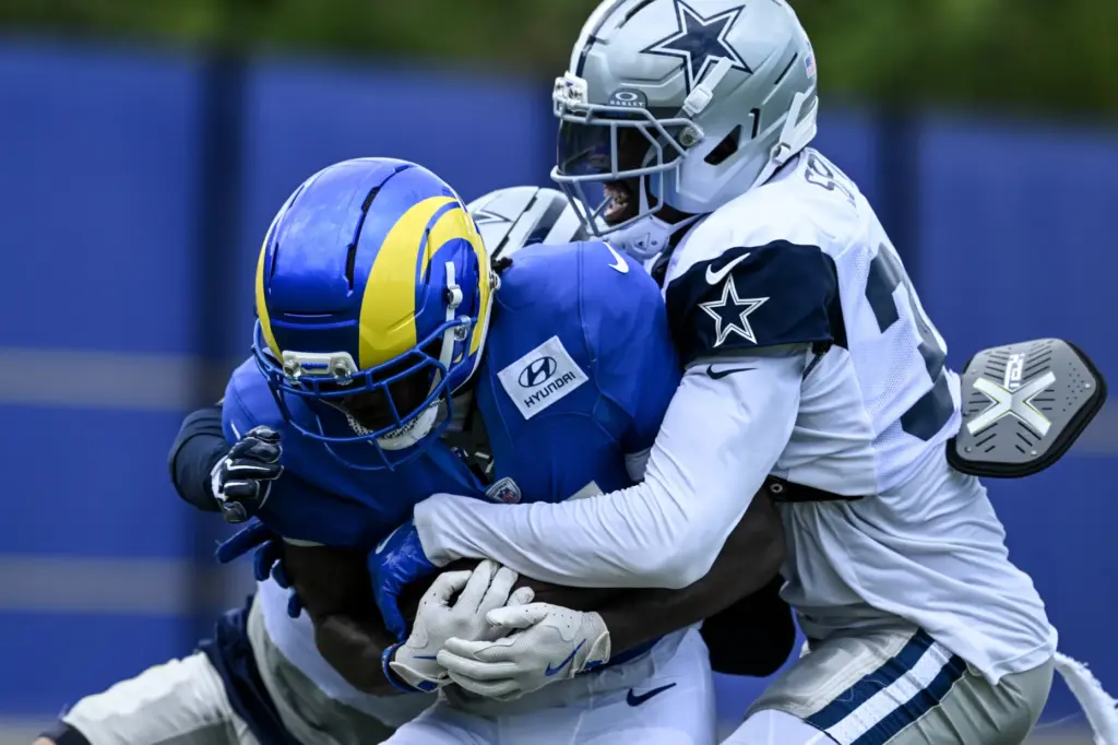 Rams running back Blake Corum, left, gets wrapped up by...