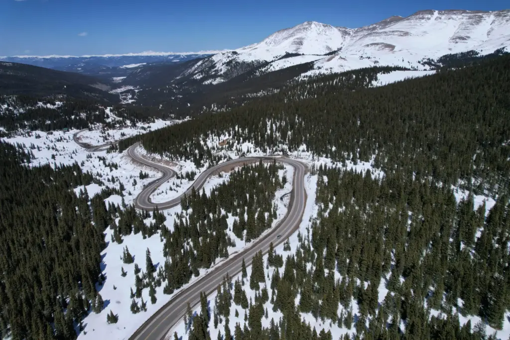 FILE – A road winds through the snow-covered Rocky Mountains...