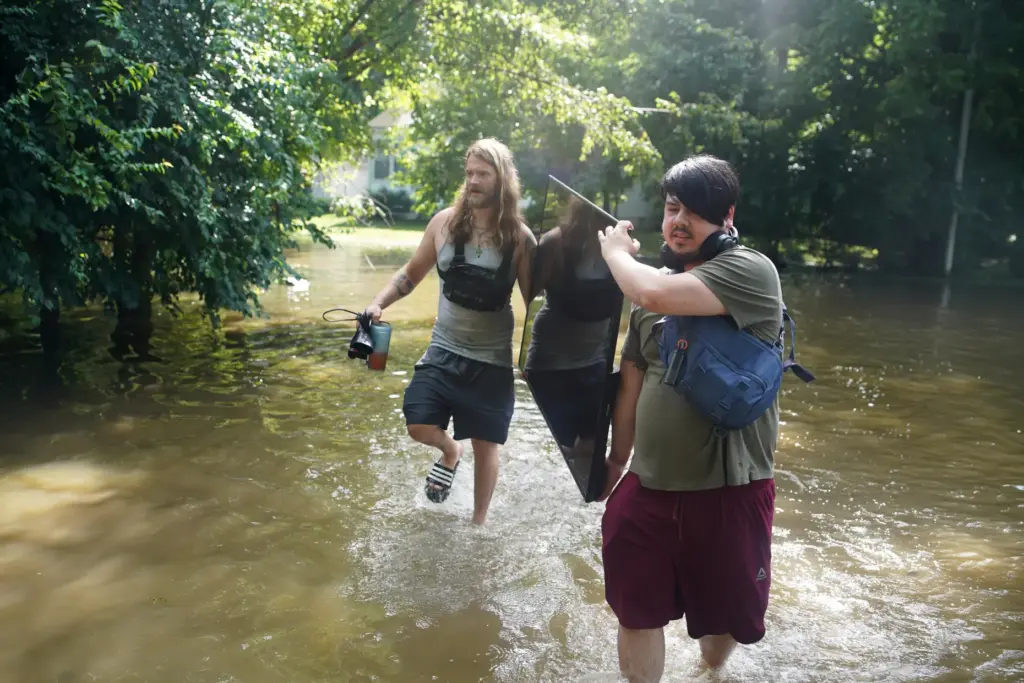 Darius Canler and Curtis Carey carry a TV from their flooded home.