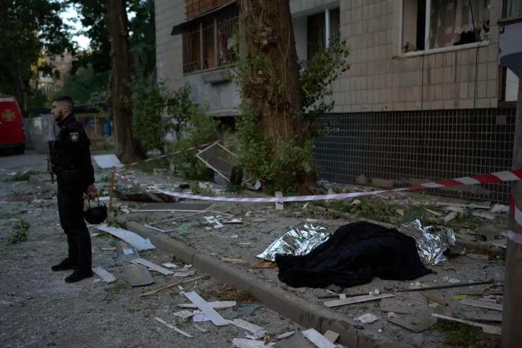 A policeman stands next to the bodies of two people killed during an overnight Russian attack.
