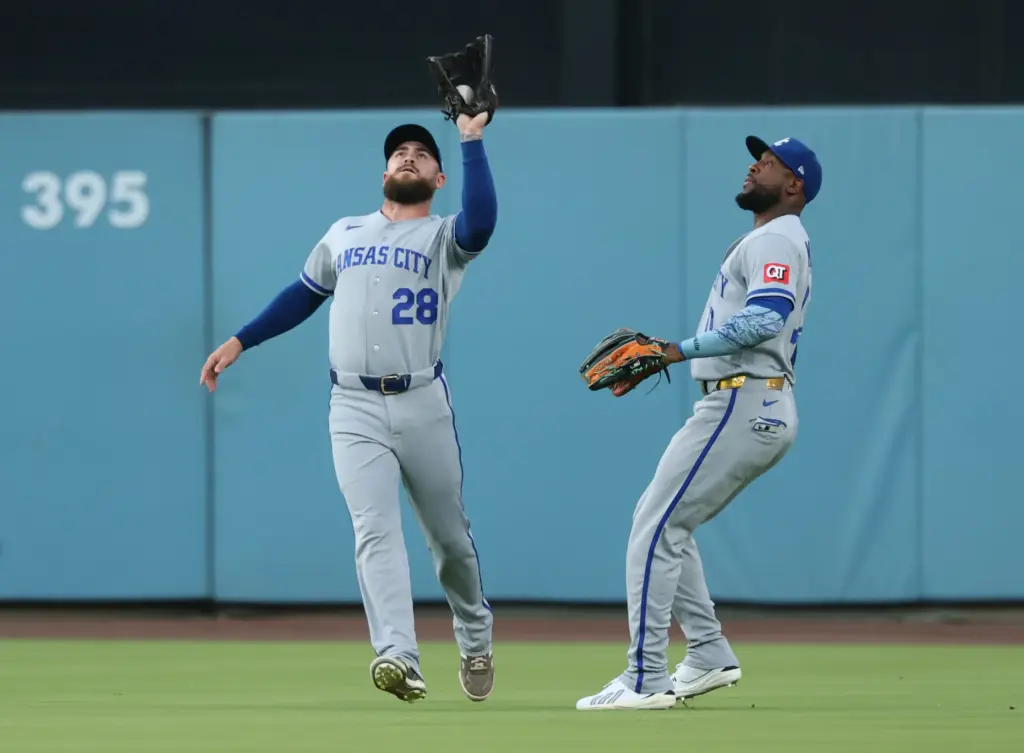 Kansas City Royals outfielder Kyle Isbel, left, makes a catch...