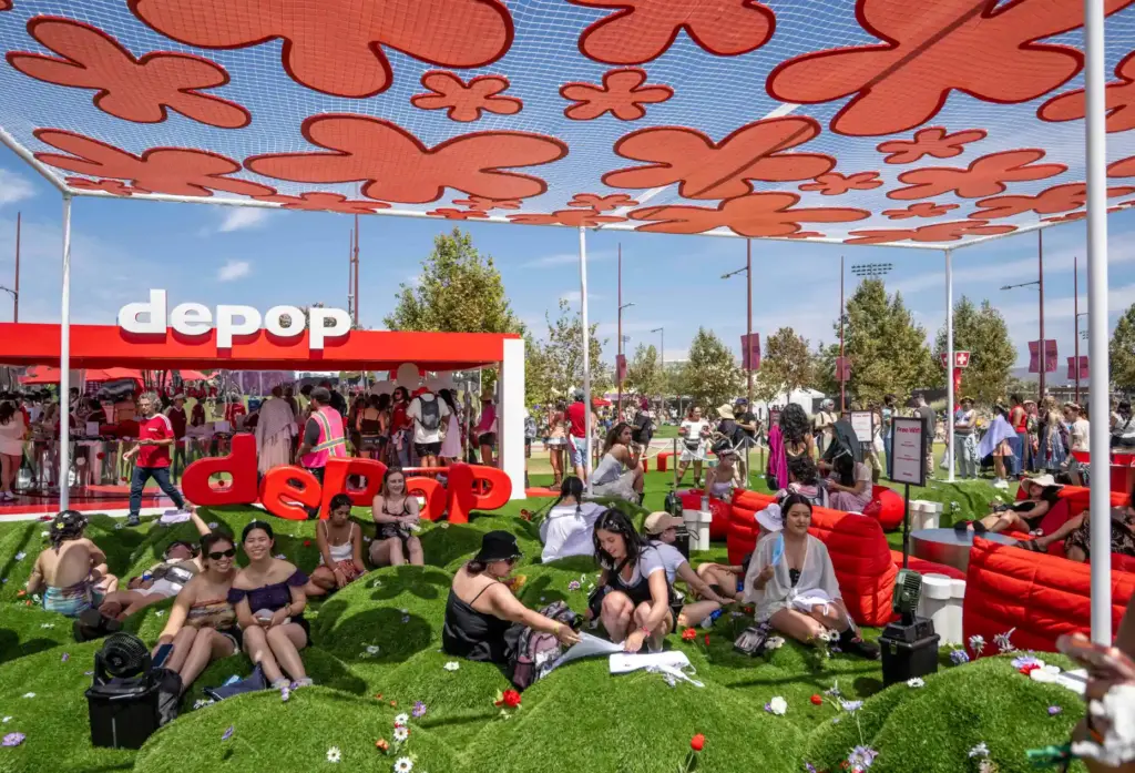 Festivalgoers rest on grassy mounds under the shade of a...