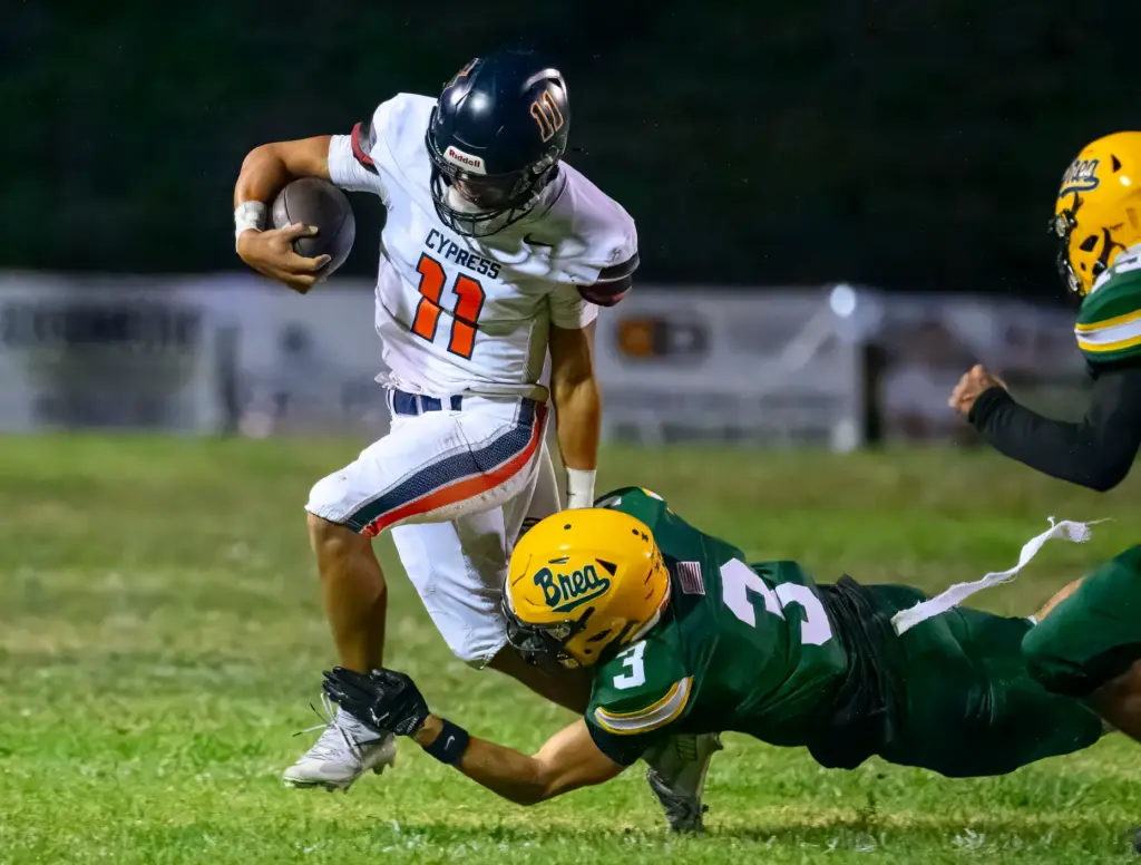Cypress quarterback Justin Hall, left, is able to avoid the...