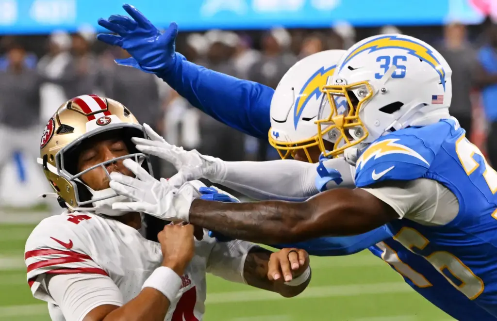 San Francisco 49ers quarterback Adrian Martinez, left, is pressured by...