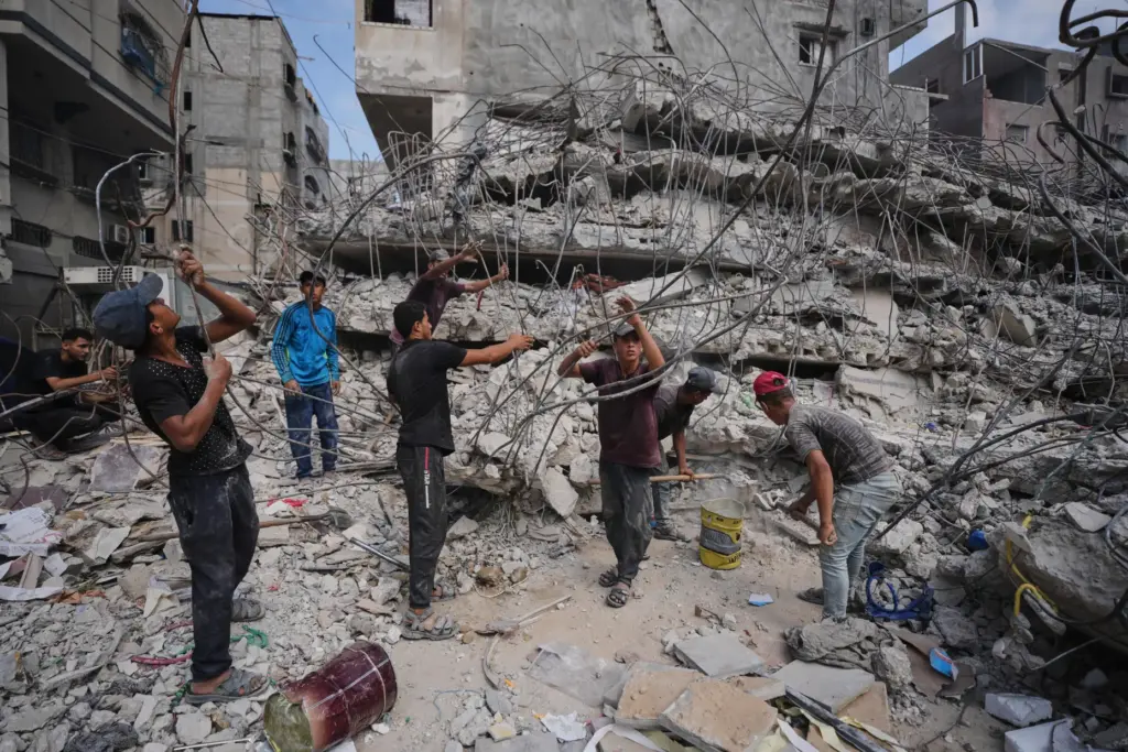 Palestinians remove iron from the rubble of buildings destroyed by Israeli airstrikes.