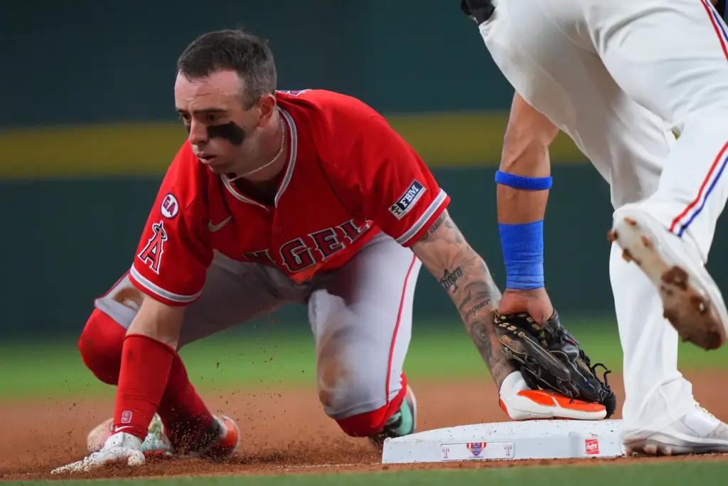 Angels Zach Neto, left, steals third base against Texas Rangers...