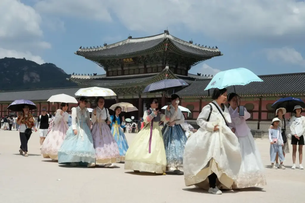 Visitors holding umbrellas to avoid sunshine leave the Gyeongbok Palace.
