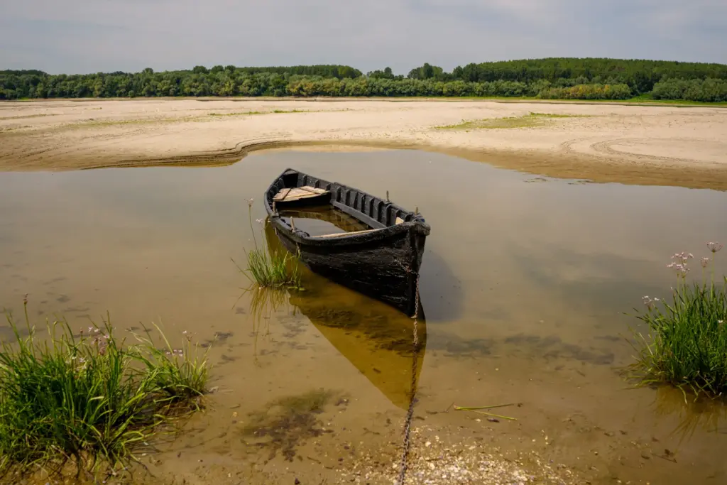 A boat is banked on the sand in an area...