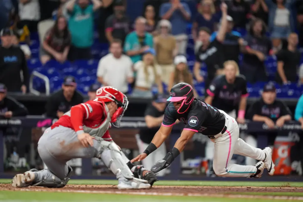 The Miami Marlins’ Leo Jimenez dives for home plate but...