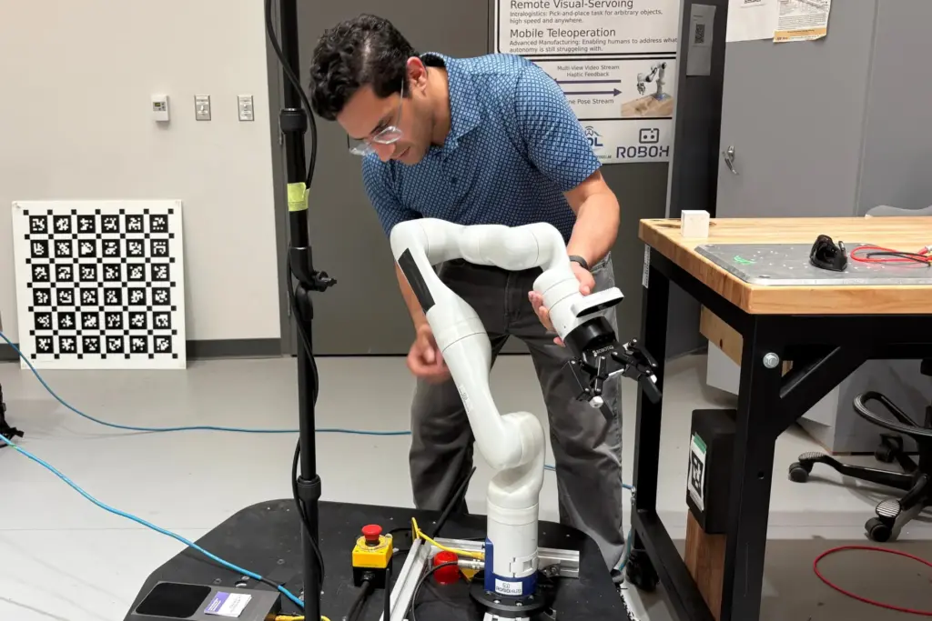 Nikhil Malhotra demonstrates his mobile manipulator robot arm in a lab.