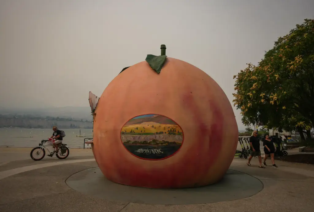 People walk and cycle past an ice cream stand in...