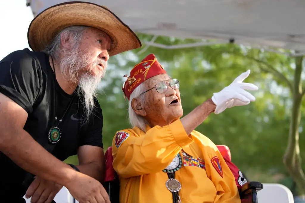 Navajo Code Talker Thomas Begay, right, talks with his son,...