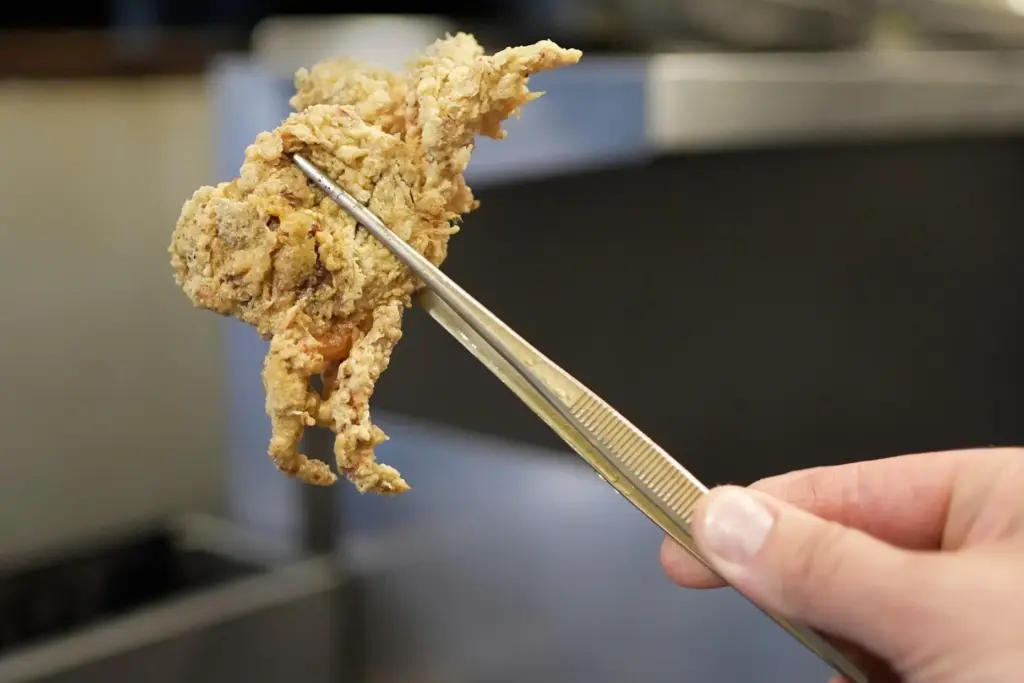 A breaded green crab is pulled from a fryer at...