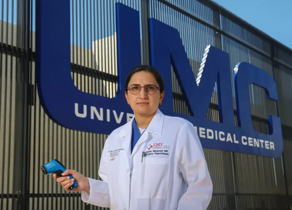 Rabia Nizamani holds an infrared thermometer.