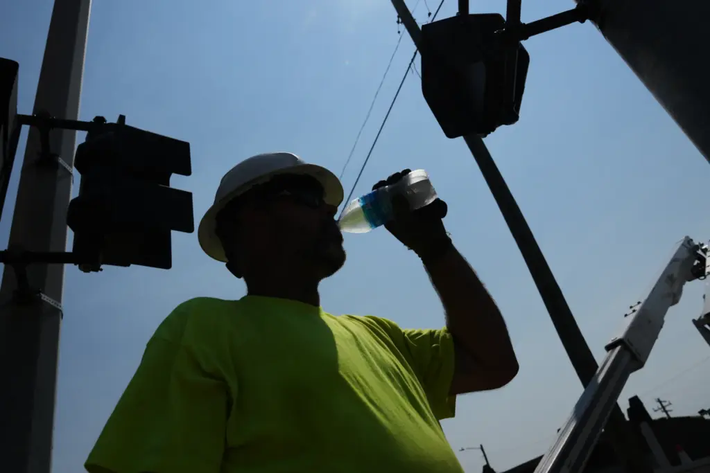 FILE – Dean Malcom drinks water while wiring street lights...