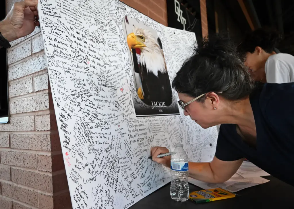 Claremont resident, Lisa Messinger, writes on the commemorative board for...