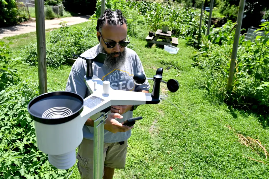 DJ Carter checks the app that links to the weather station at the Plantation Park Heights Urban Farm.