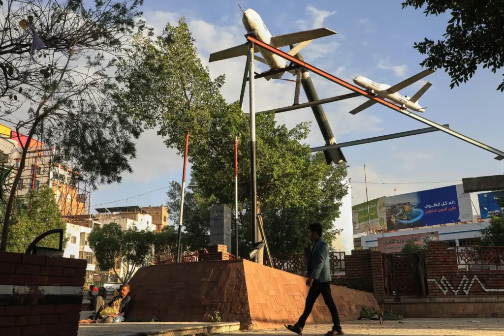 A Yemeni man walks past a monument featuring mock rockets in Sanaa.