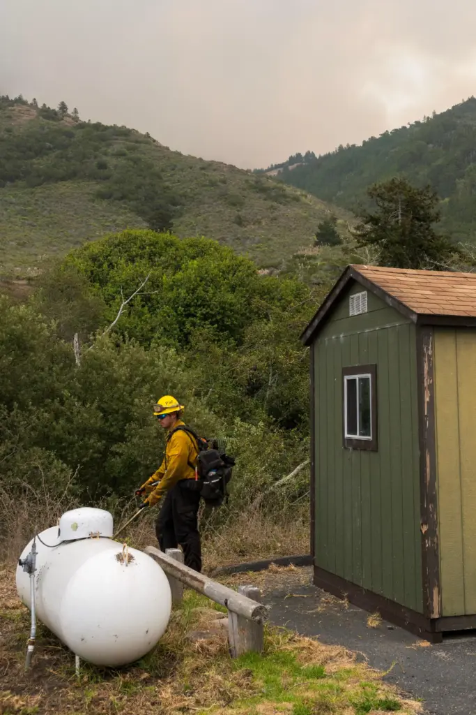 A firefighter trims bushes around the U.S. Forest Service fire station.