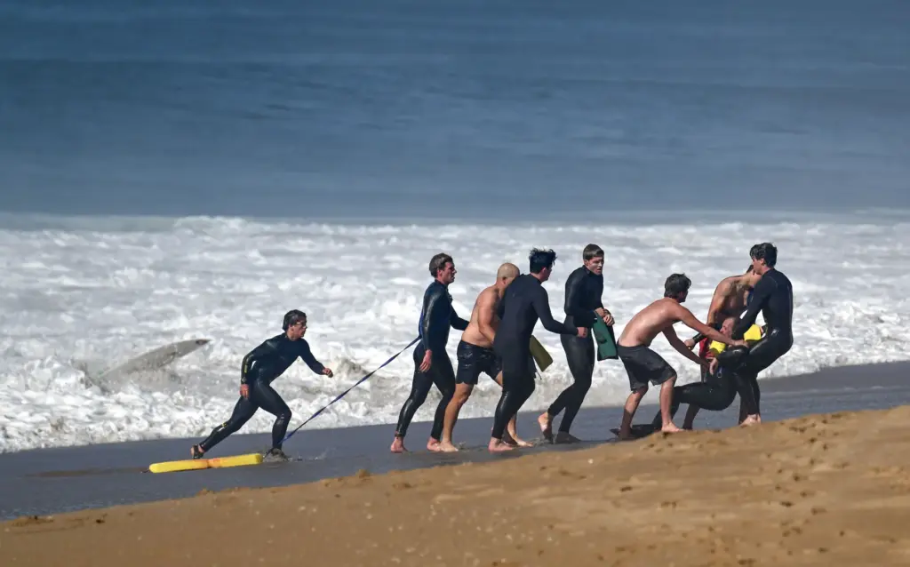 Lifeguards pull a swimmer out of the surf during a...