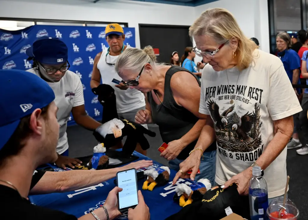 Barstow resident, Laurie Knutsen, (right) buys a commemorative t-shirt and...