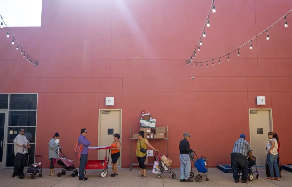 Community members line up to receive food from a food...