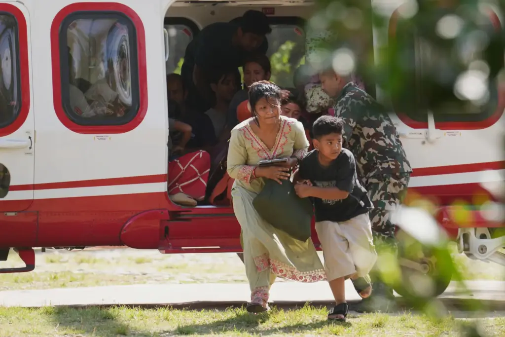 Army soldiers help a family disembark from a helicopter after they are rescued.