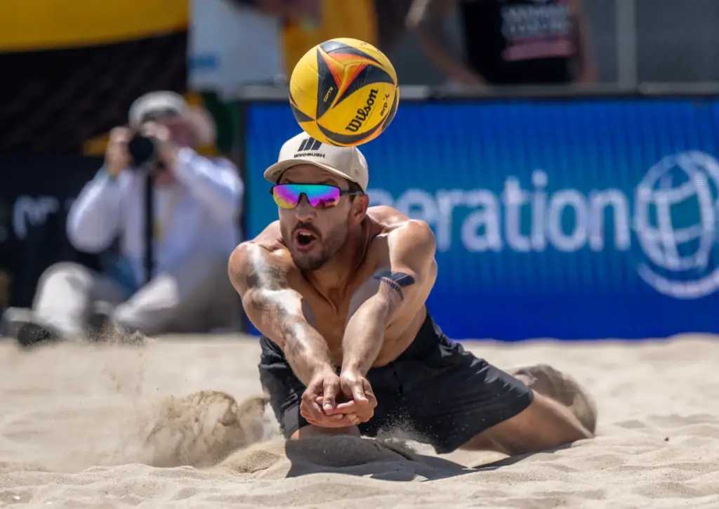 Miles Evans dives in the sand to dig the ball,...