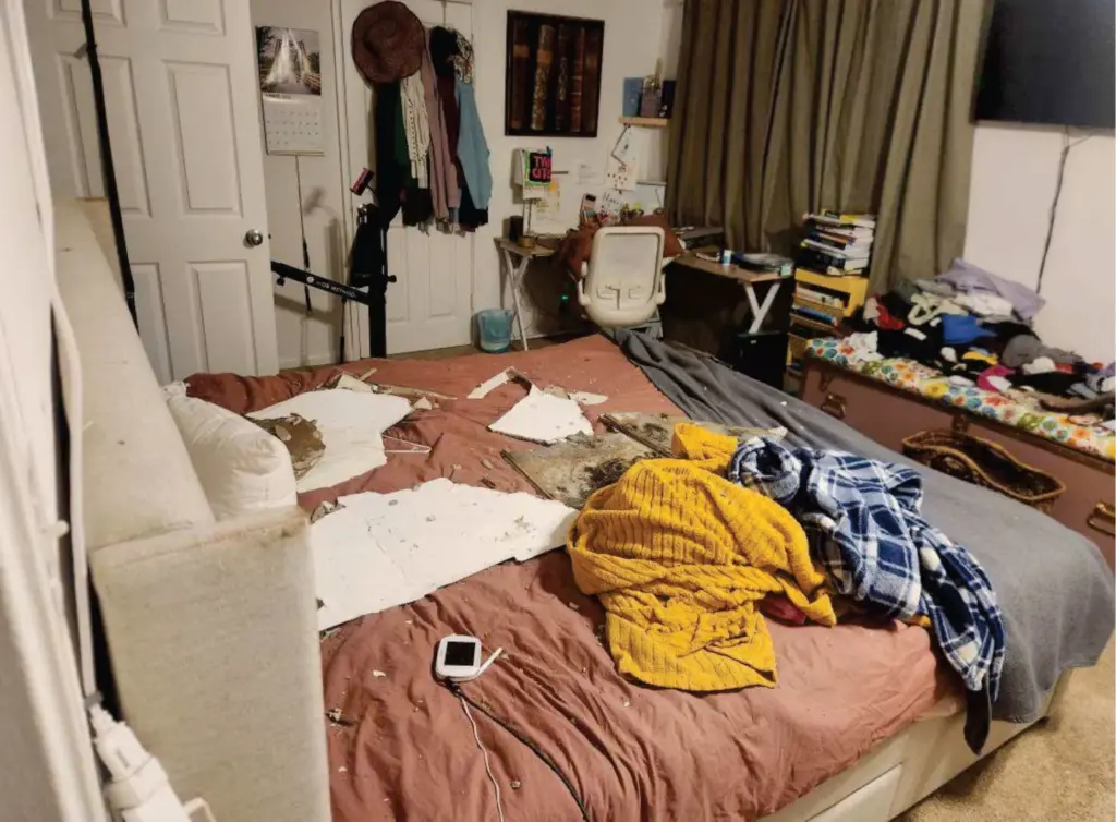 Drywall from a caved-in ceiling covers a bed.