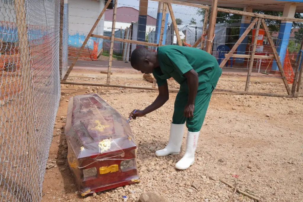 A health worker on the dignified and safe burial team monitors a casket.