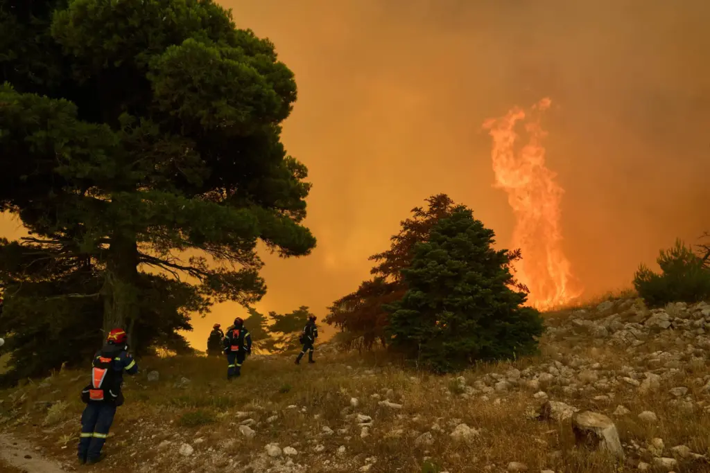 Firefighters approach towering flames on Mount Kithairon near Porto Germeno, Greece.