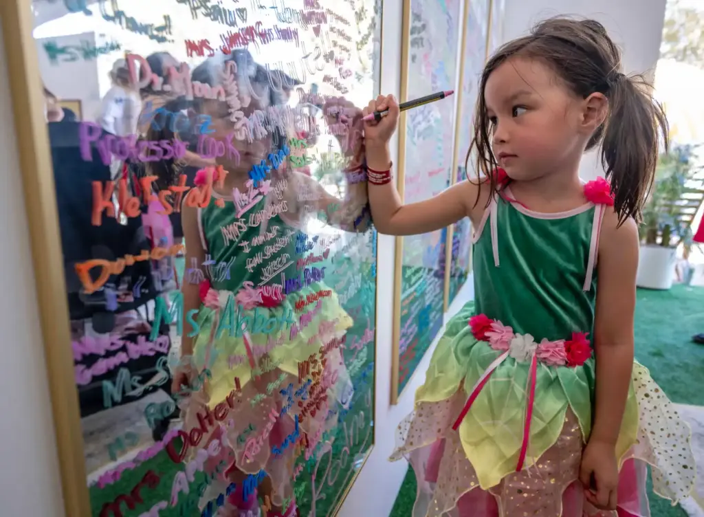 Harper Van Houten, 4, of Las Vegas writes on a...