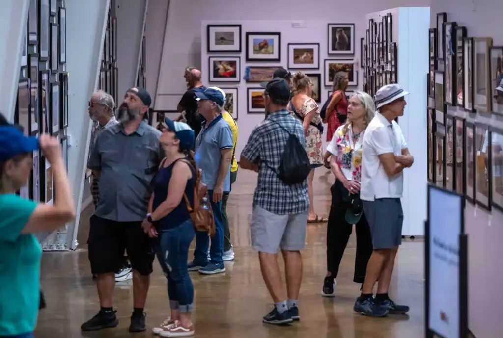 Fairgoers check out hundreds of photographs on display at the...