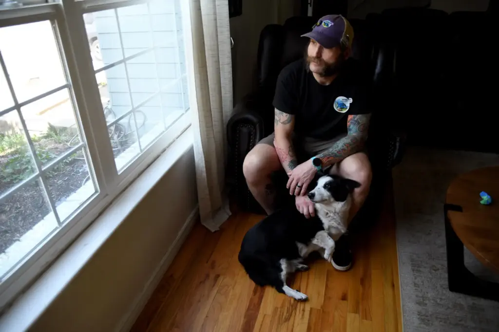 Joe Shearer poses for a portrait with his dog in his home.