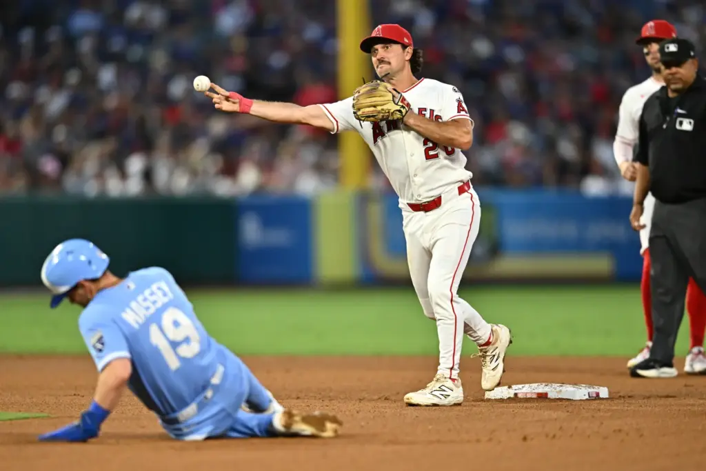 Angels second baseman Adam Frazier, center, throws for a double...