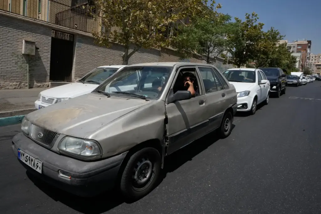 Cars line up outside a gas station in Tehran, Iran,...