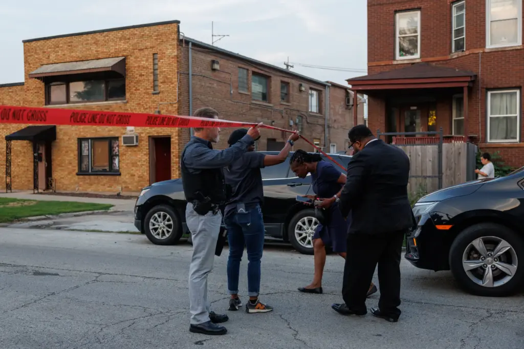 A Chicago police officer and a city official, left, speak...