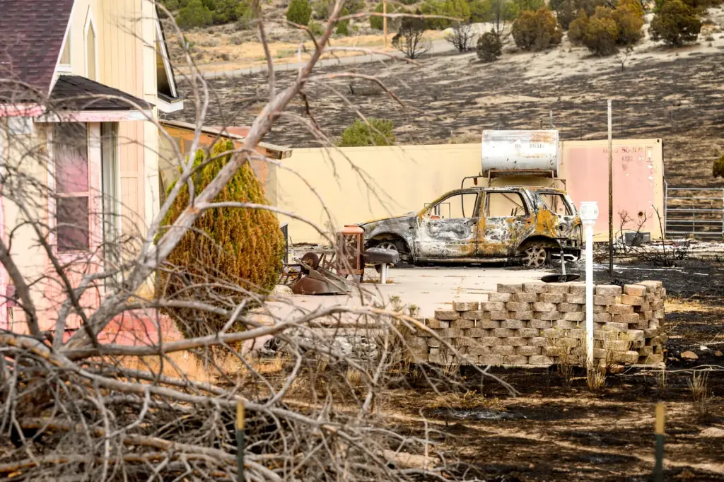 A scorched car sits outside a home that survived the...