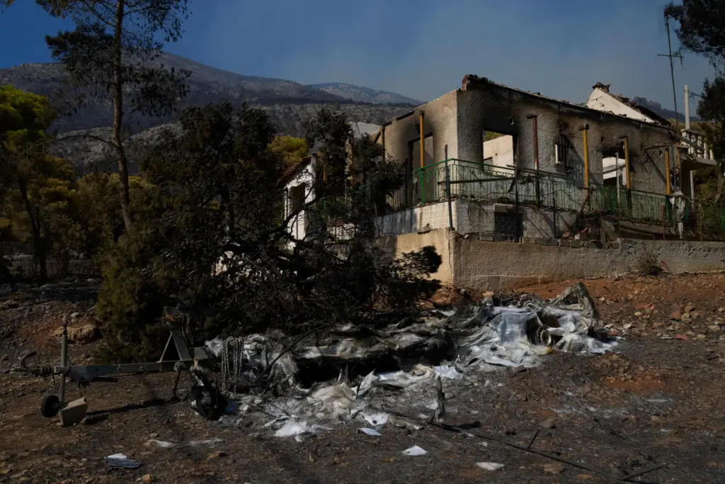 A house and a boat, destroyed by a wildfire, are seen in Porto Germeno, Greece.