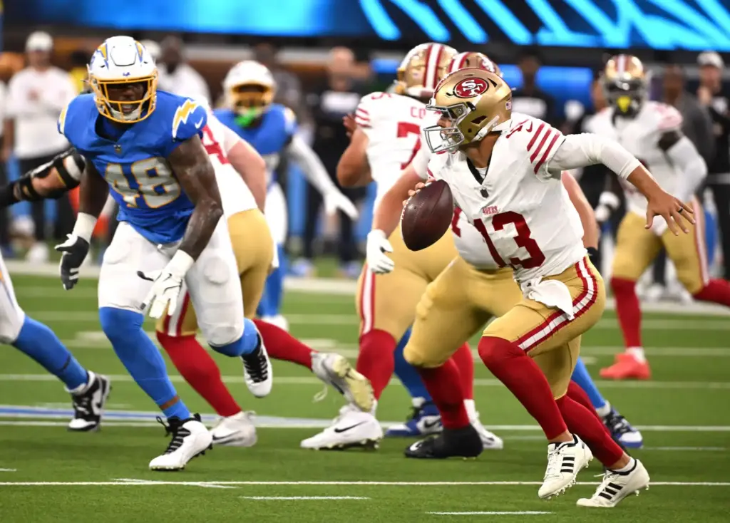 San Francisco 49ers starting quarterback Brock Purdy, right, scrambles as...